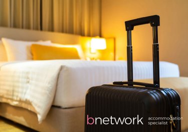 Luggage at the forefront of a bed in a hotel room