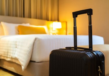 Valise devant un lit confortable de chambre d'hôtel